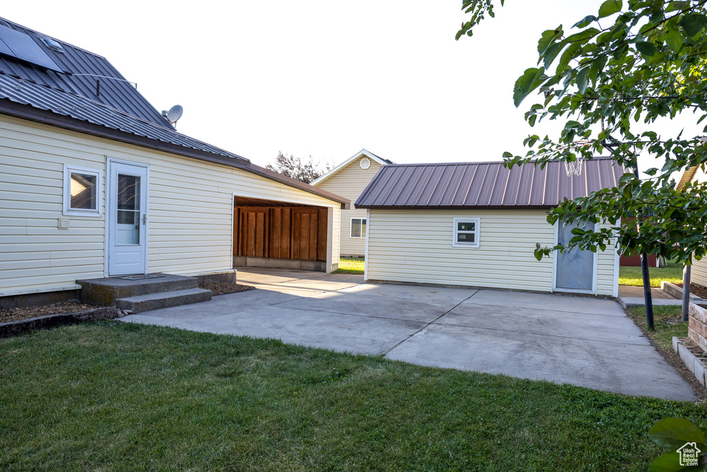 Back of property with a metal roof, a patio, and a lawn