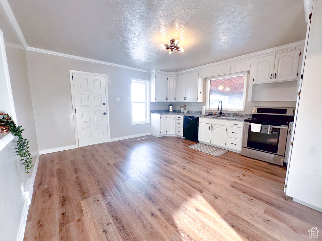 Kitchen with electric stove, black dishwasher, white cabinetry, light wood-style flooring, and crown molding