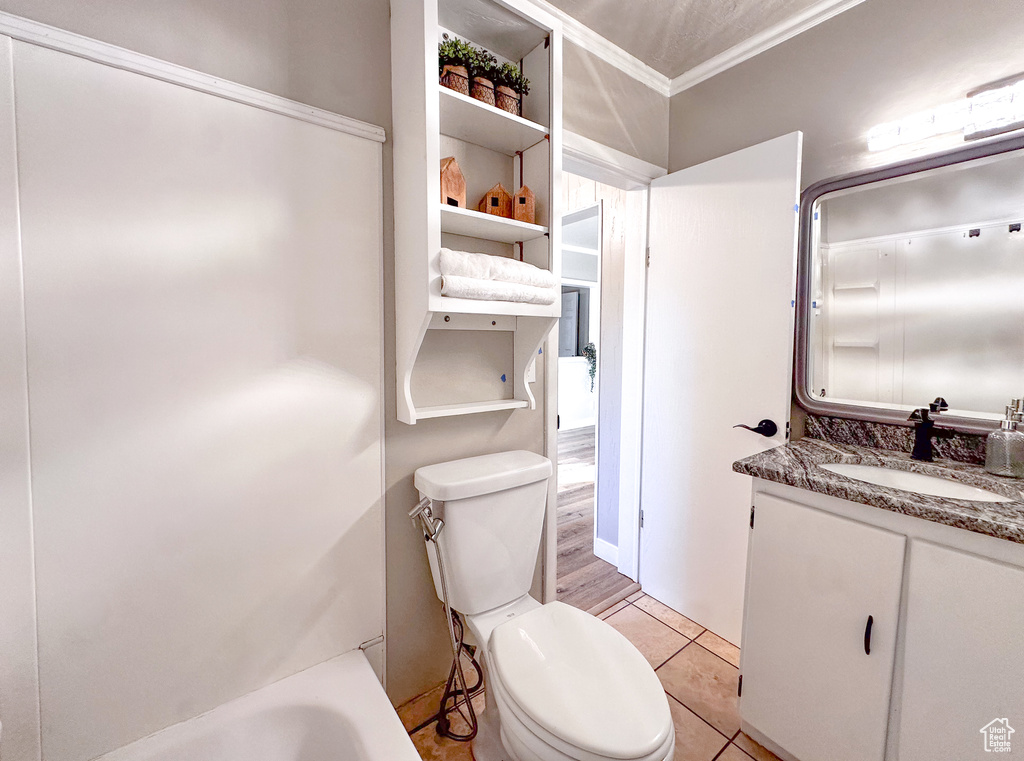 Bathroom with crown molding, vanity, a bathtub, and tile patterned flooring