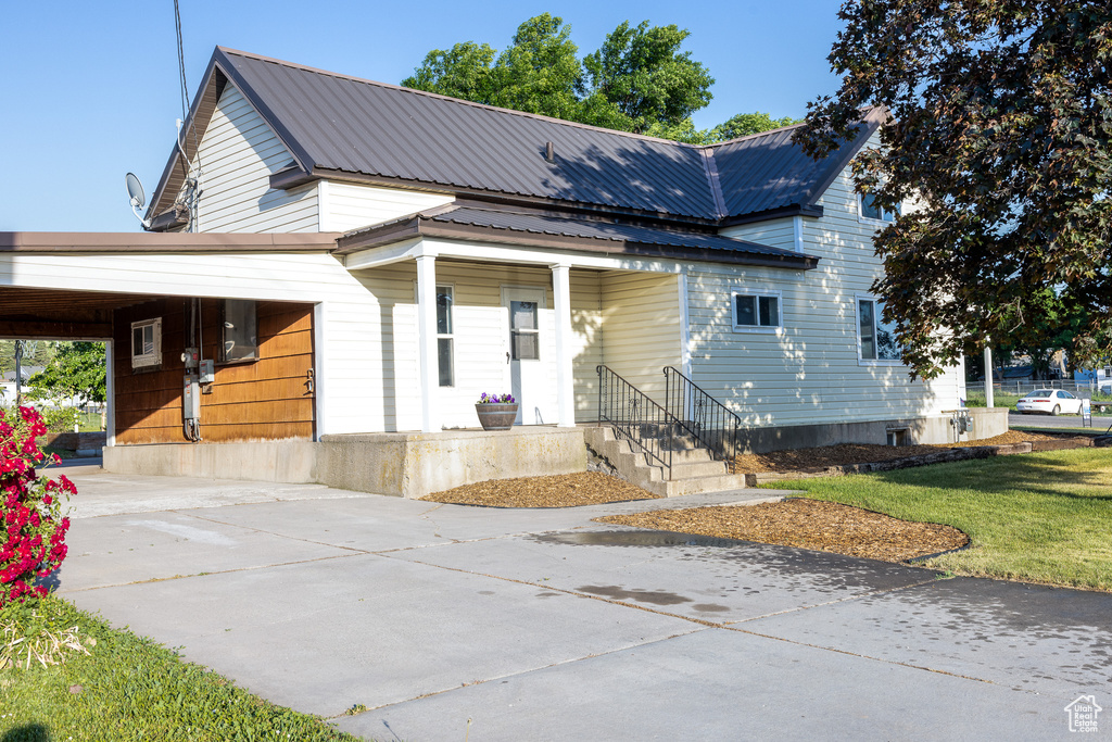 View of front of house featuring driveway, a metal roof, a porch, and a carport