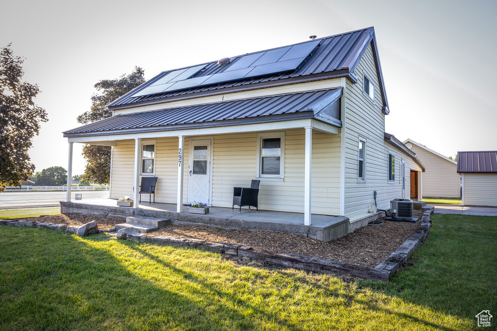 View of front of home featuring covered porch, solar panels, a front yard, and a metal roof