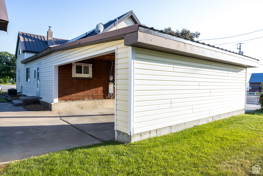 View of home\\\'s exterior with a metal roof, concrete driveway, a lawn, and a chimney