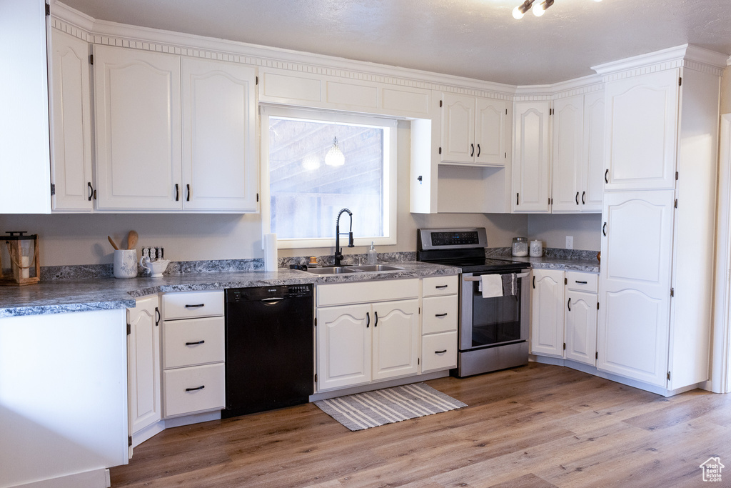 Kitchen with electric stove, black dishwasher, white cabinets, and light wood-style flooring