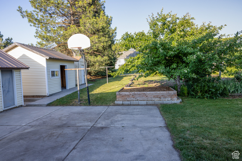 View of green lawn featuring a patio area and an outdoor structure