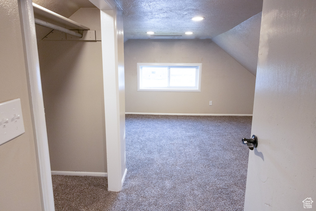 Bonus room with carpet floors, a textured ceiling, and vaulted ceiling