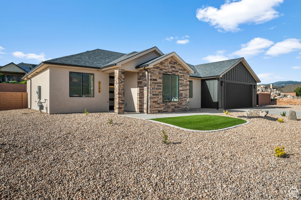 View of front of house featuring roof with shingles, a garage, driveway, board and batten siding, and stucco siding