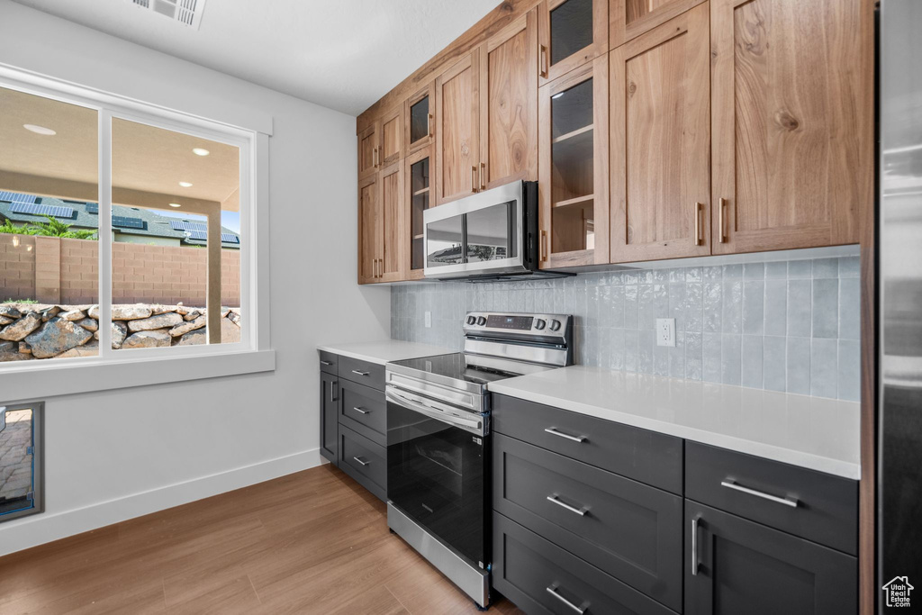Kitchen featuring stainless steel appliances, backsplash, light countertops, and light wood finished floors