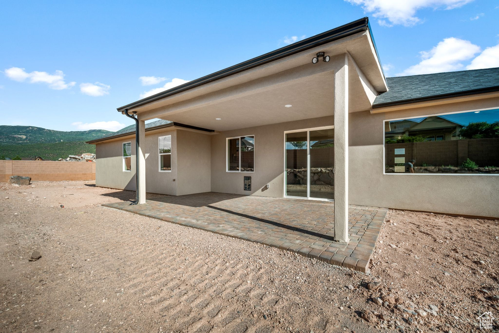 Back of property featuring stucco siding, a patio area, and a mountain view