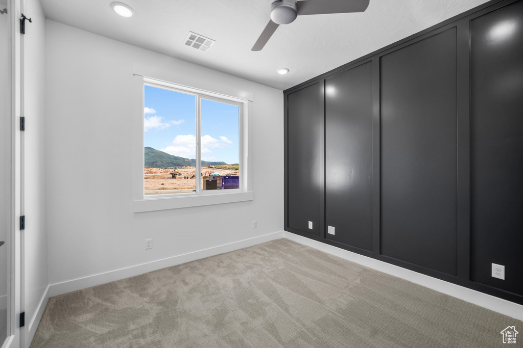 Unfurnished bedroom with light carpet, recessed lighting, a mountain view, and a ceiling fan