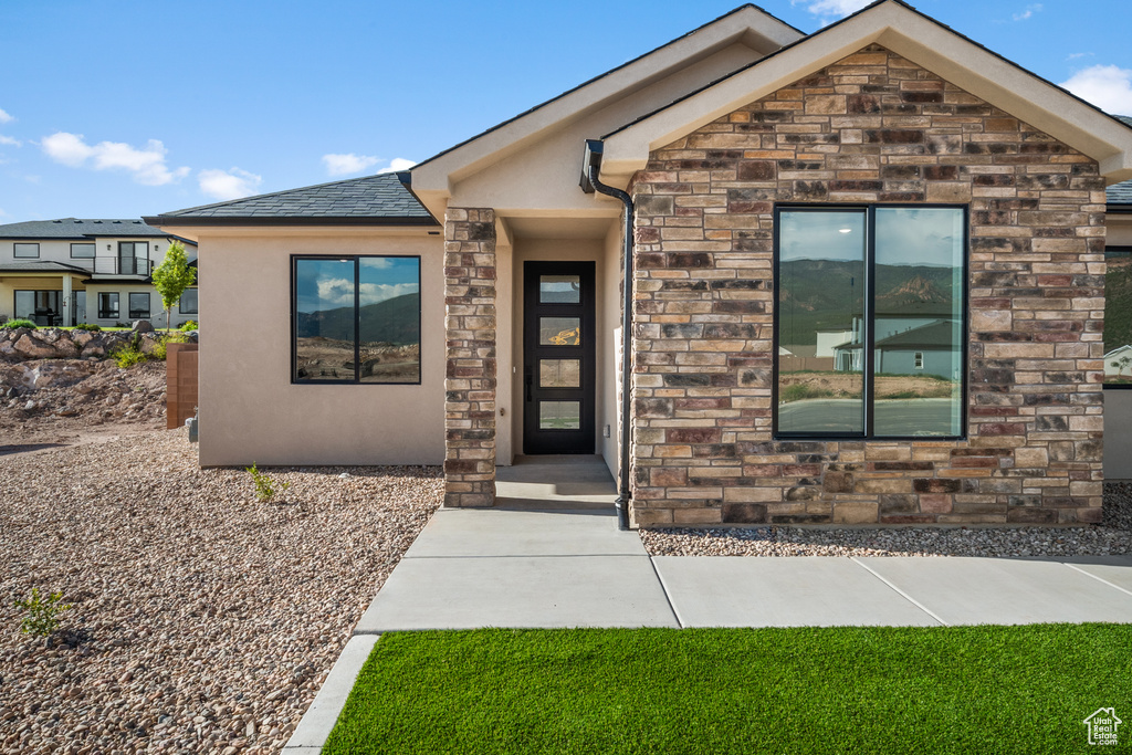View of exterior entry with stucco siding and stone siding