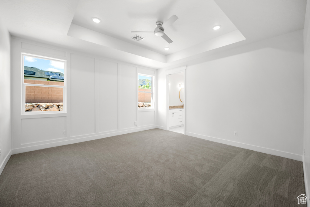 Unfurnished bedroom featuring a raised ceiling, carpet floors, recessed lighting, and ensuite bath