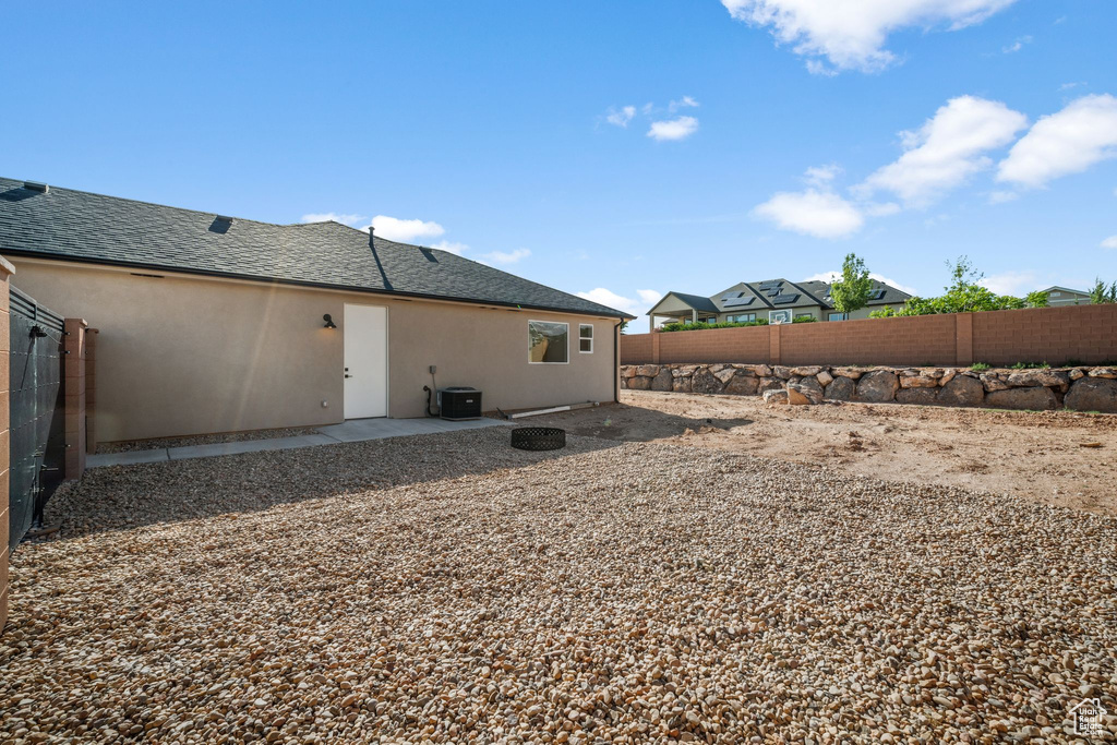 Rear view of house with stucco siding, a fenced backyard, a patio area, and a shingled roof