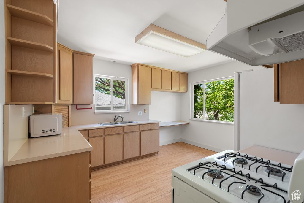 Kitchen with white appliances, light brown cabinetry, and healthy amount of natural light