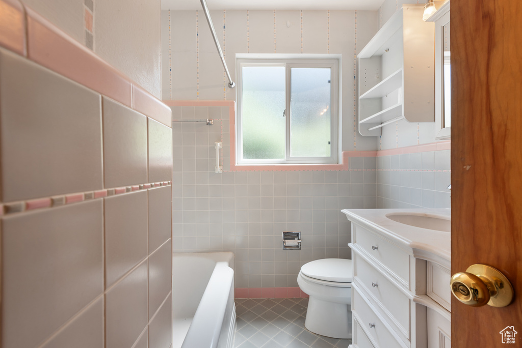 Bathroom with tile walls, a tub, tile patterned flooring, vanity, and wainscoting