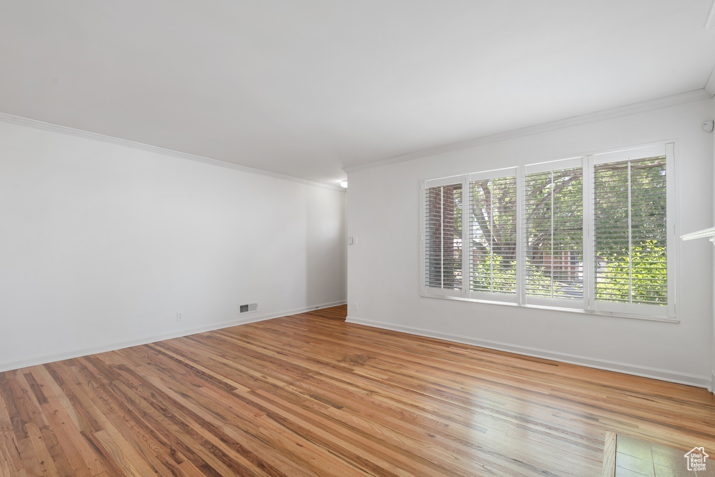Empty room with ornamental molding and light wood-type flooring