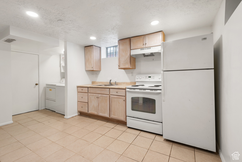 Kitchen with white appliances, light brown cabinetry, under cabinet range hood, a textured ceiling, and light countertops