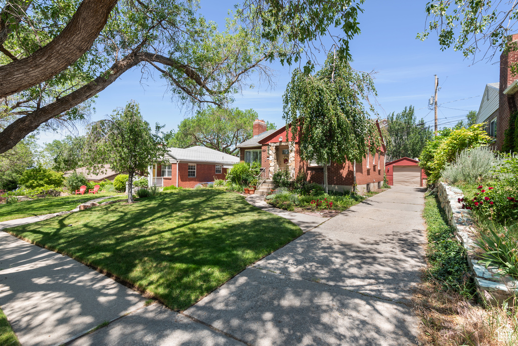 View of front of home with brick siding, an outdoor structure, a front lawn, and a garage
