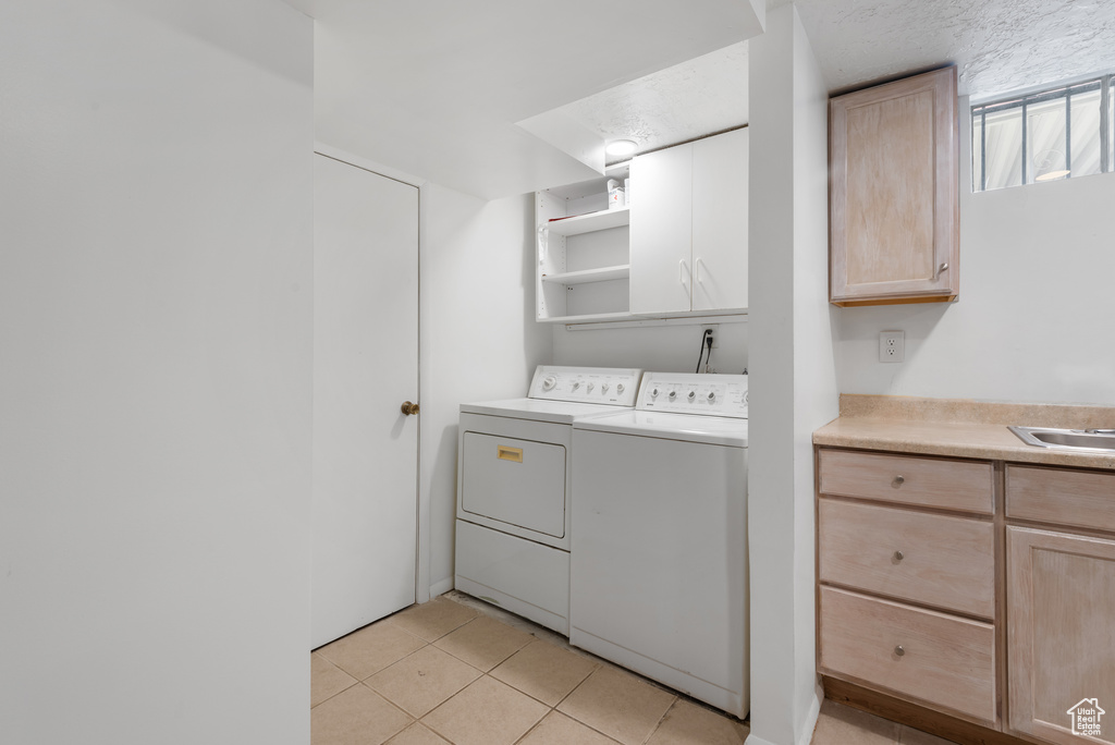 Laundry room with cabinet space, washing machine and dryer, and light tile patterned floors