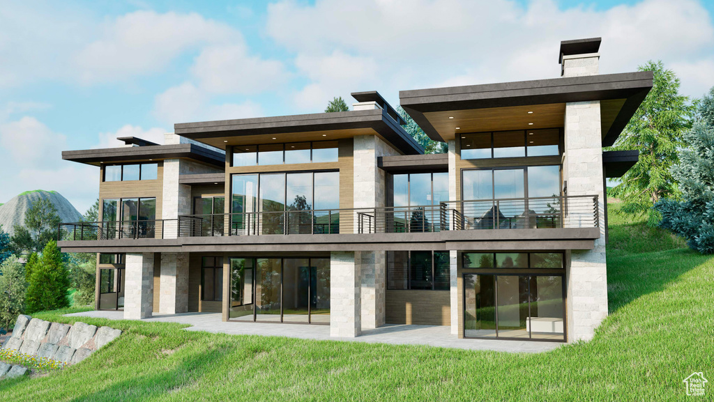 Back of house featuring a lawn, a patio, a chimney, and a balcony