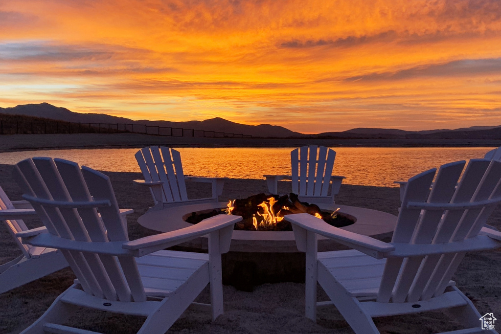 Patio terrace at dusk featuring an outdoor fire pit and a water and mountain view