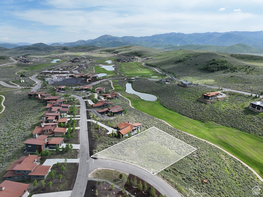 Aerial overview of property\'s location featuring a water and mountain view, property parcel outlined, and nearby suburban area