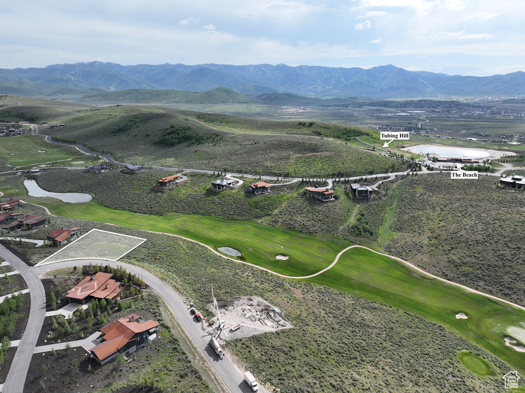 Aerial view of property and surrounding area featuring a water and mountain view and a local golf course