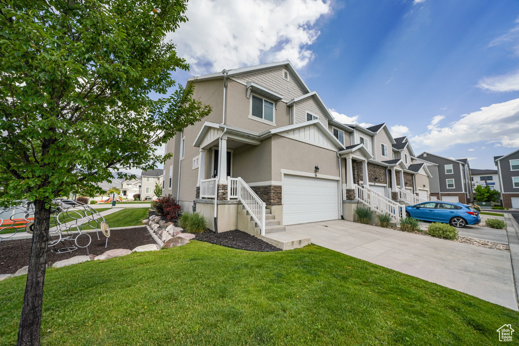 View of front facade with stucco siding, concrete driveway, stone siding, a residential view, and a front yard