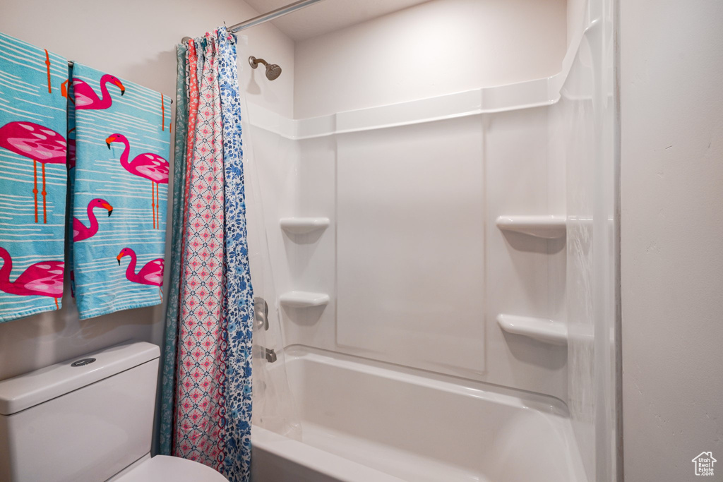 Full bath featuring shower / bath combo with shower curtain and toilet