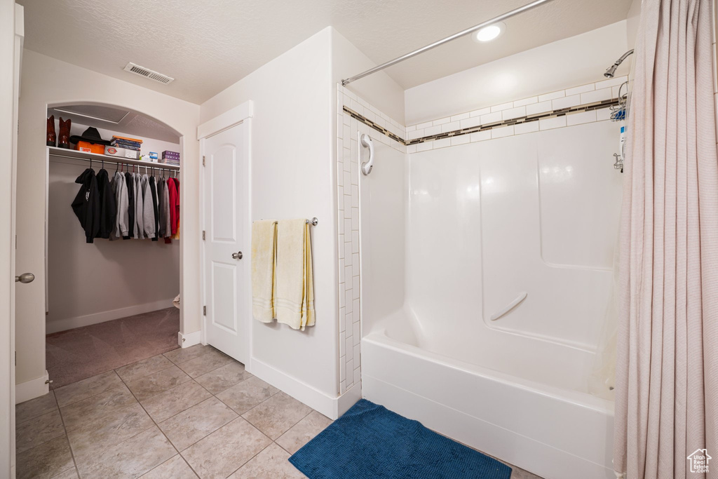 Full bath featuring shower / tub combo, tile patterned floors, and a spacious closet