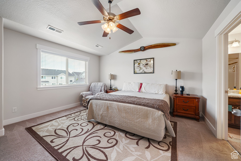 Bedroom featuring light colored carpet, vaulted ceiling, connected bathroom, and a ceiling fan