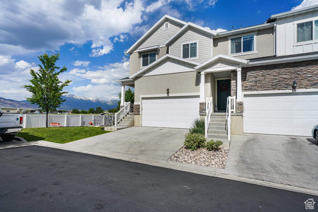 View of front of home with stone siding, board and batten siding, a mountain view, and a garage