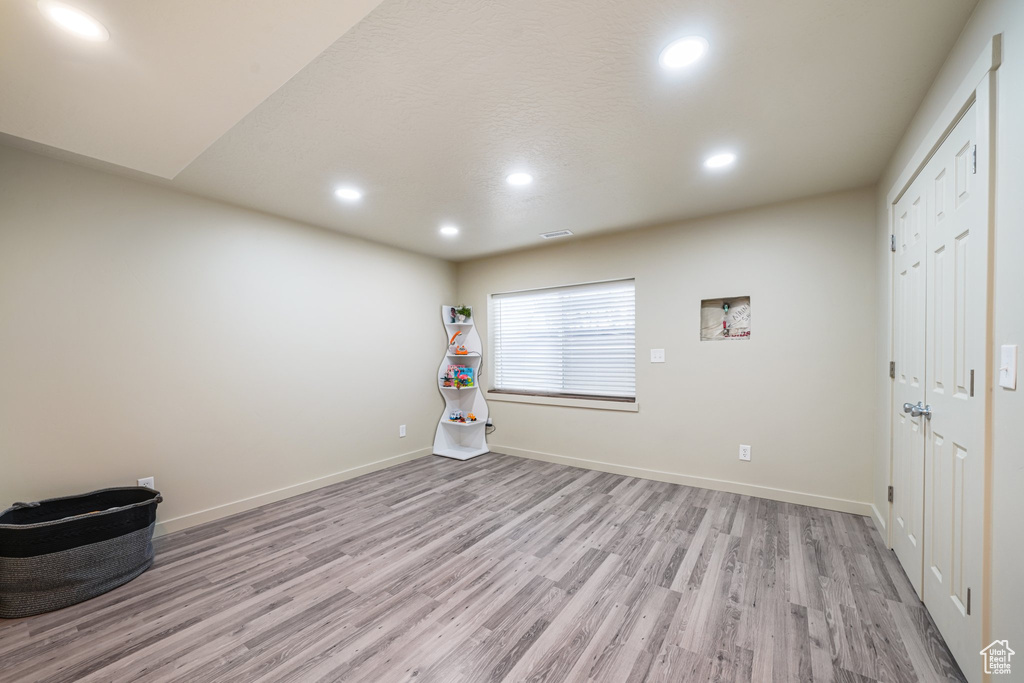 Empty room with light wood-style floors and recessed lighting