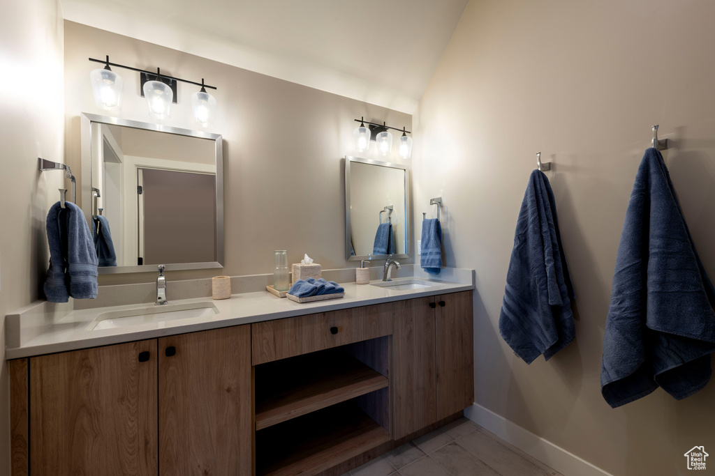 Bathroom featuring double vanity and lofted ceiling