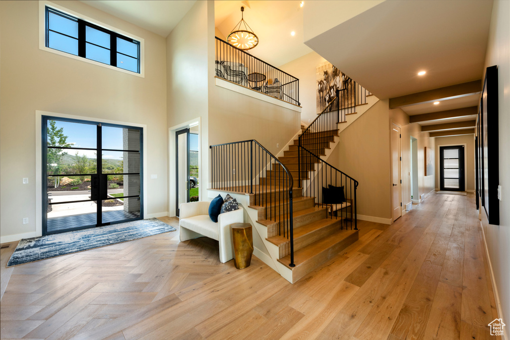 Foyer with stairs, a chandelier, parquet flooring, recessed lighting, and a high ceiling