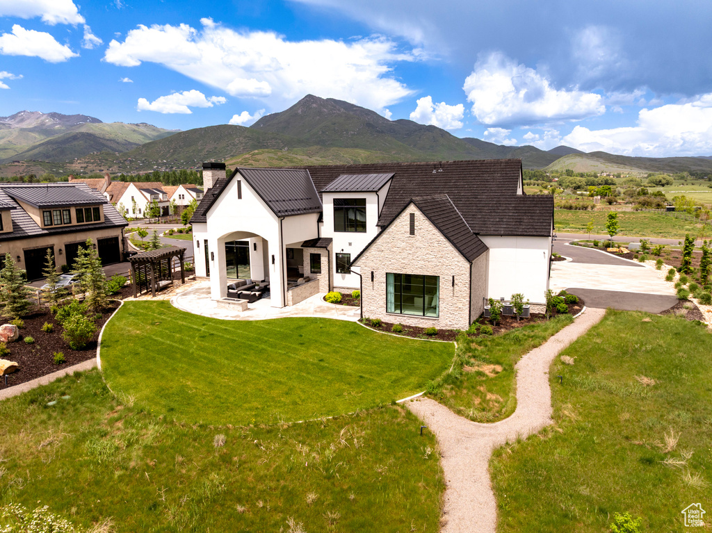 Rear view of property with a mountain view, a chimney, a yard, and a patio area