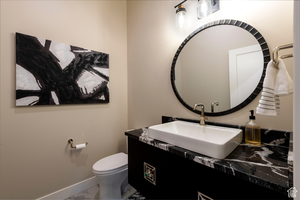 Half bathroom with marble look tile flooring and vanity