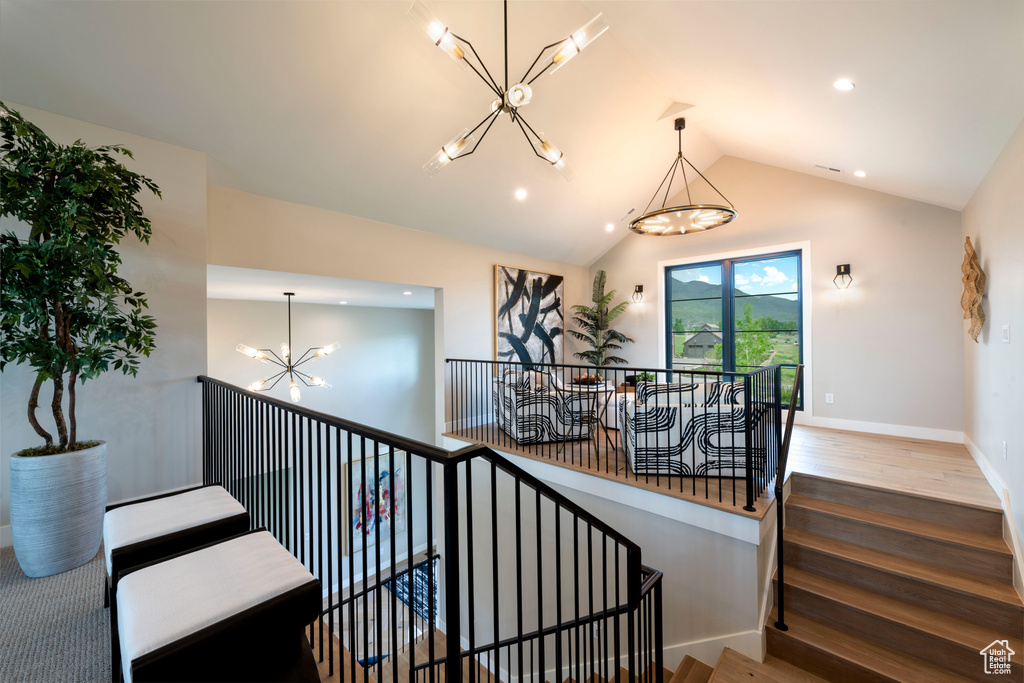 Stairs featuring a chandelier, wood finished floors, recessed lighting, and lofted ceiling