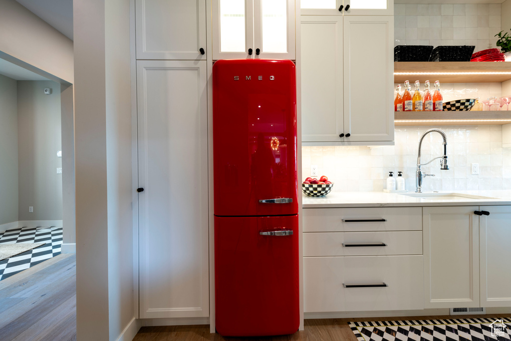 Kitchen featuring refrigerator, white cabinets, light countertops, and backsplash