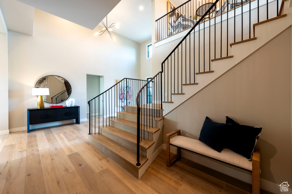 Staircase with a towering ceiling, a chandelier, and wood finished floors
