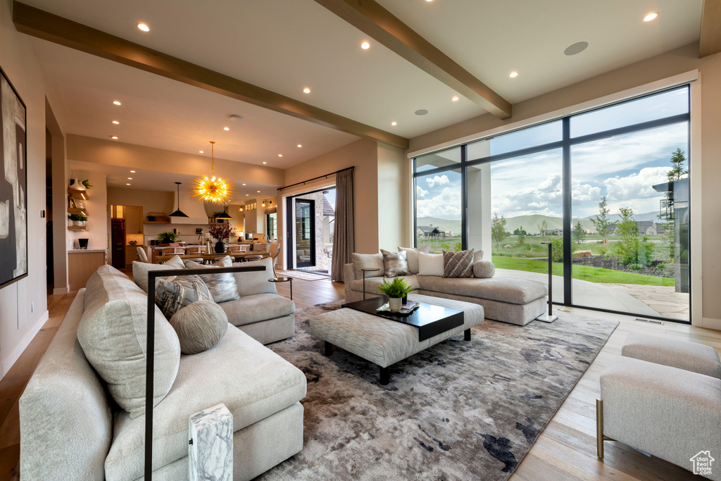Living room with a chandelier, beam ceiling, recessed lighting, and wood finished floors