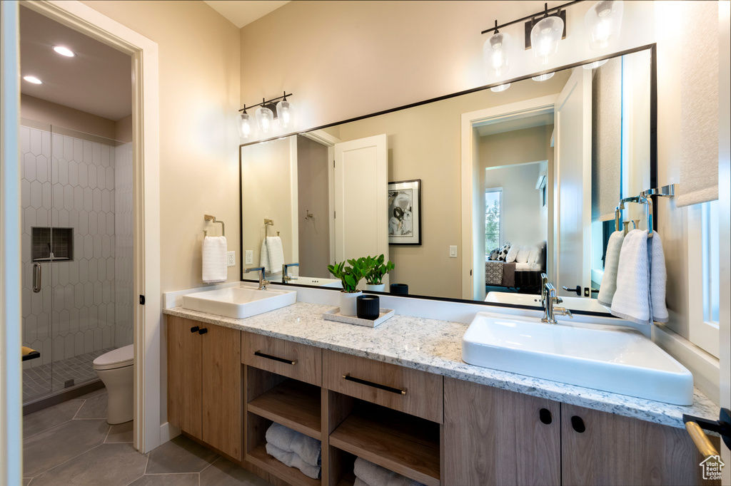 Ensuite bathroom featuring a stall shower, double vanity, tile patterned floors, and recessed lighting