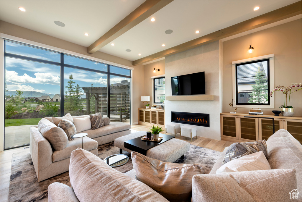 Living room featuring a glass covered fireplace, light wood-style floors, recessed lighting, and beam ceiling
