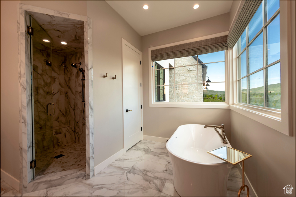 Bathroom featuring a freestanding tub, recessed lighting, a marble finish shower, and marble look tile flooring