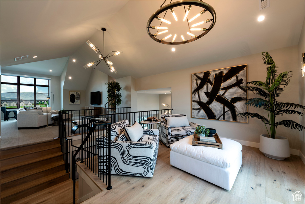 Living area featuring a chandelier, vaulted ceiling, wood finished floors, and recessed lighting