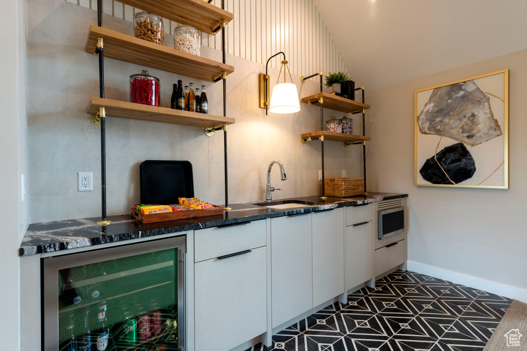 Indoor bar with beverage cooler, vaulted ceiling, and stainless steel microwave