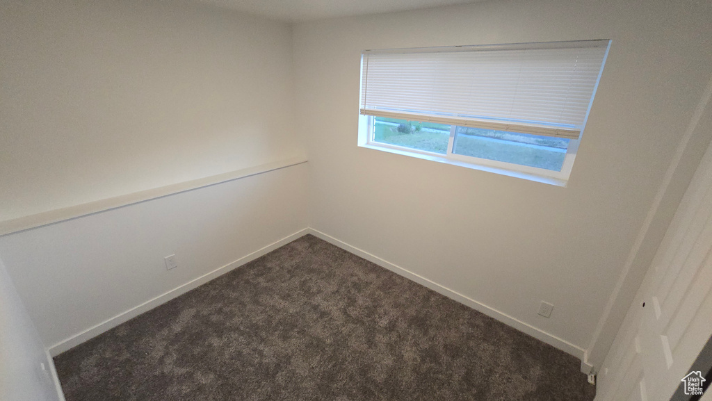Empty room with dark colored carpet and baseboards