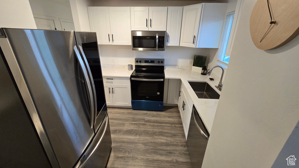 Kitchen featuring appliances with stainless steel finishes, dark wood finished floors, light countertops, and white cabinets