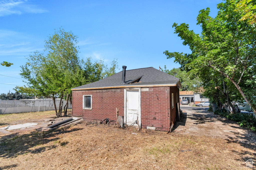 Back of property with brick siding and a shingled roof