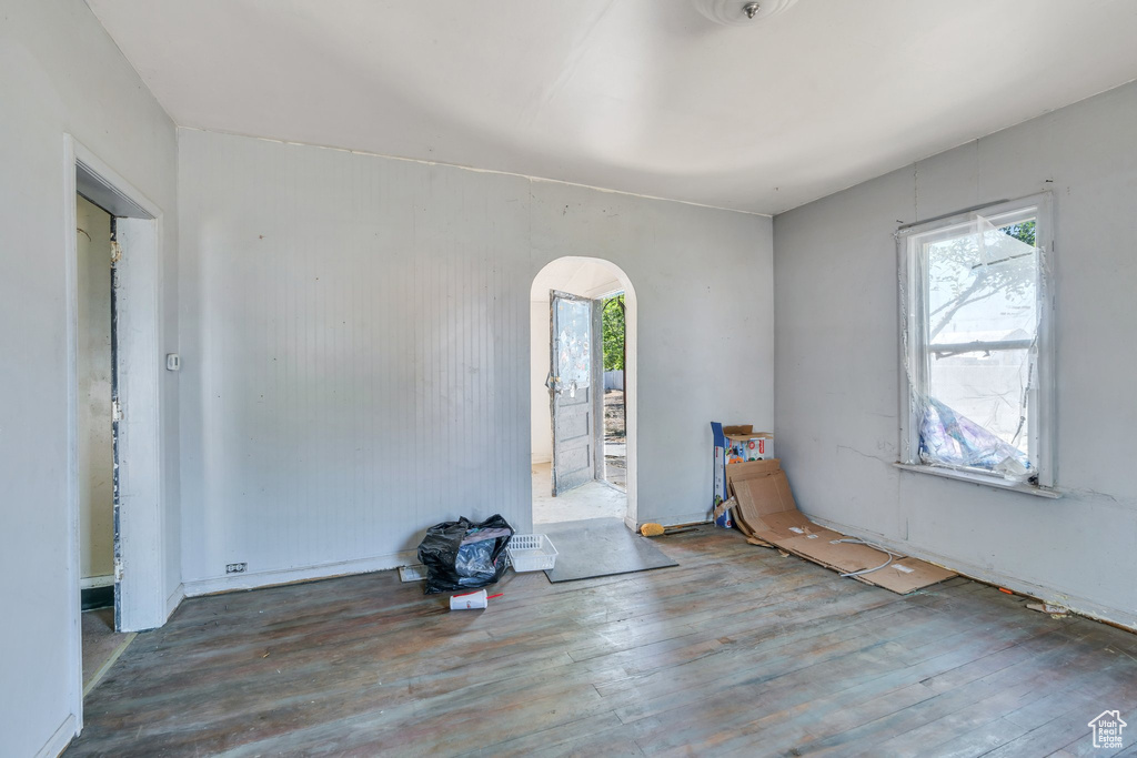 Unfurnished room with arched walkways and wood finished floors