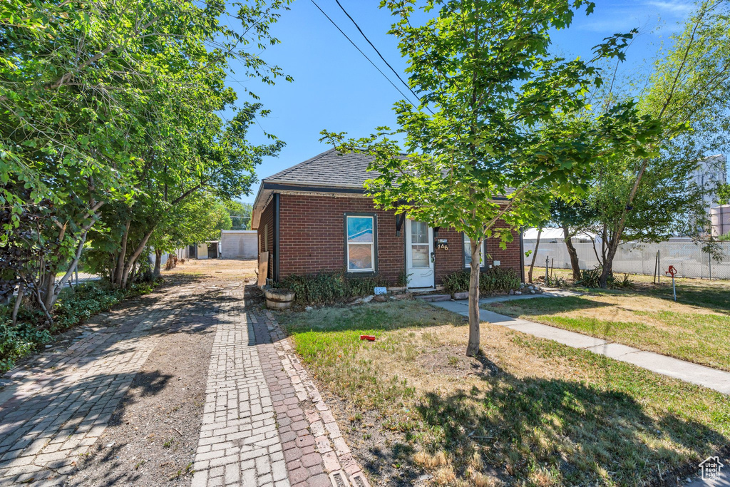 View of front of home featuring brick siding, driveway, and a shingled roof